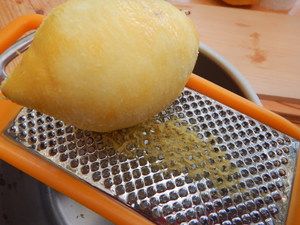 Zitronenschale wird auf einer Reibe abgerieben