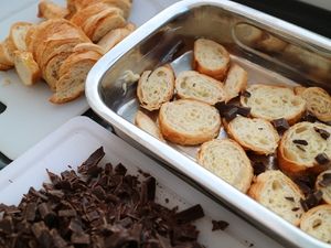 Baguettescheiben in einer Auflaufform, davor gehackte Schokolade
