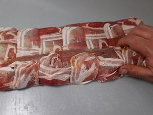 Schweinefilet wird in Geflecht aus Baconscheiben eingerollt