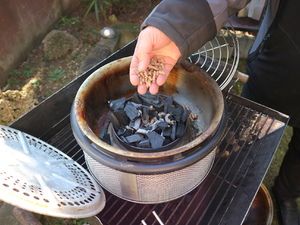 Holzpellets werden auf die Glut im Tischgrill gegeben
