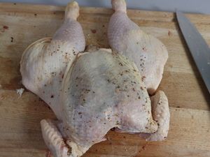 Flach aufgeschnittenes Hähnchen auf dem Brett