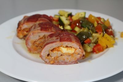 Gefülltes Schweinefilet im Speckmantel mit Gemüse auf einem Teller