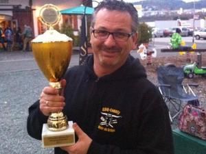 Teammitglied hält lachend einen goldenen Pokal