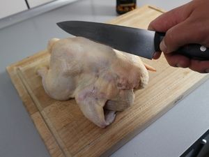 Das Rückgrat des Hähnchens wird mit dem Messer herausgeschnitten