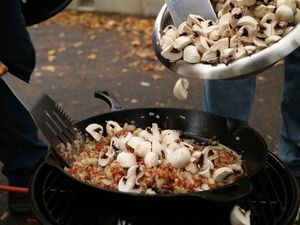 Champignons werden in die Pfanne gegeben