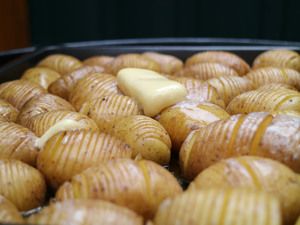 Eingeschnittene Kartoffeln mit Butterflöckchen auf dem Blech