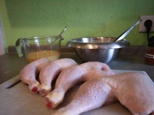 Rohe Hähnchenschenkel, dahinter Ei und Panade