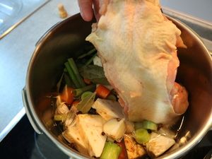 Suppenhuhn wird in den Topf mit Gemüse gelegt