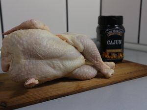Rohes Hähnchen neben einer Dose Cajun-Gewürz