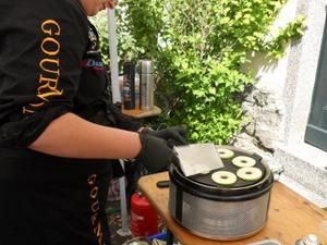 Cobb-Grill mit Zucchinischeiben auf einem Tisch im Garten