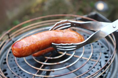 Smoked Sausage wird mit der Grillzange vom Rost genommen