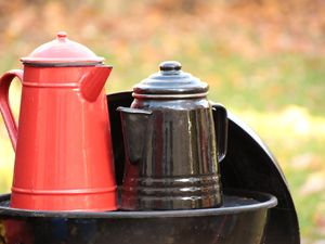 Rote und schwarze Emaillekanne auf dem Grill