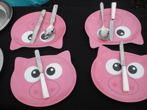 Vier Teller in Form von rosa Schweinchengesichtern mit Besteck