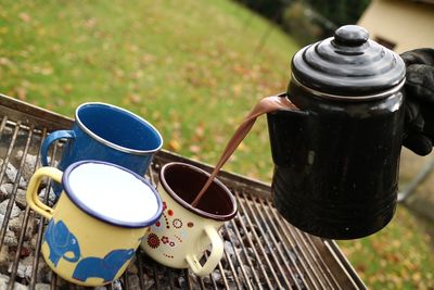 Heiße Schokolade wird aus einer Emaillekanne in Becher gegossen