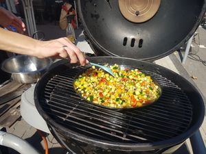 Grillgemüse wird in der Pfanne auf dem Kugelgrill gerührt