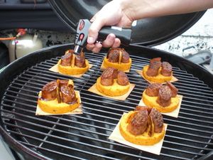 Gefüllte Teigschälchen auf dem Rost werden mit einem Thermometer geprüft